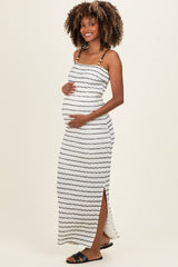 woman wearing a white striped maternity maxi dress with a side slit and holding her baby bump