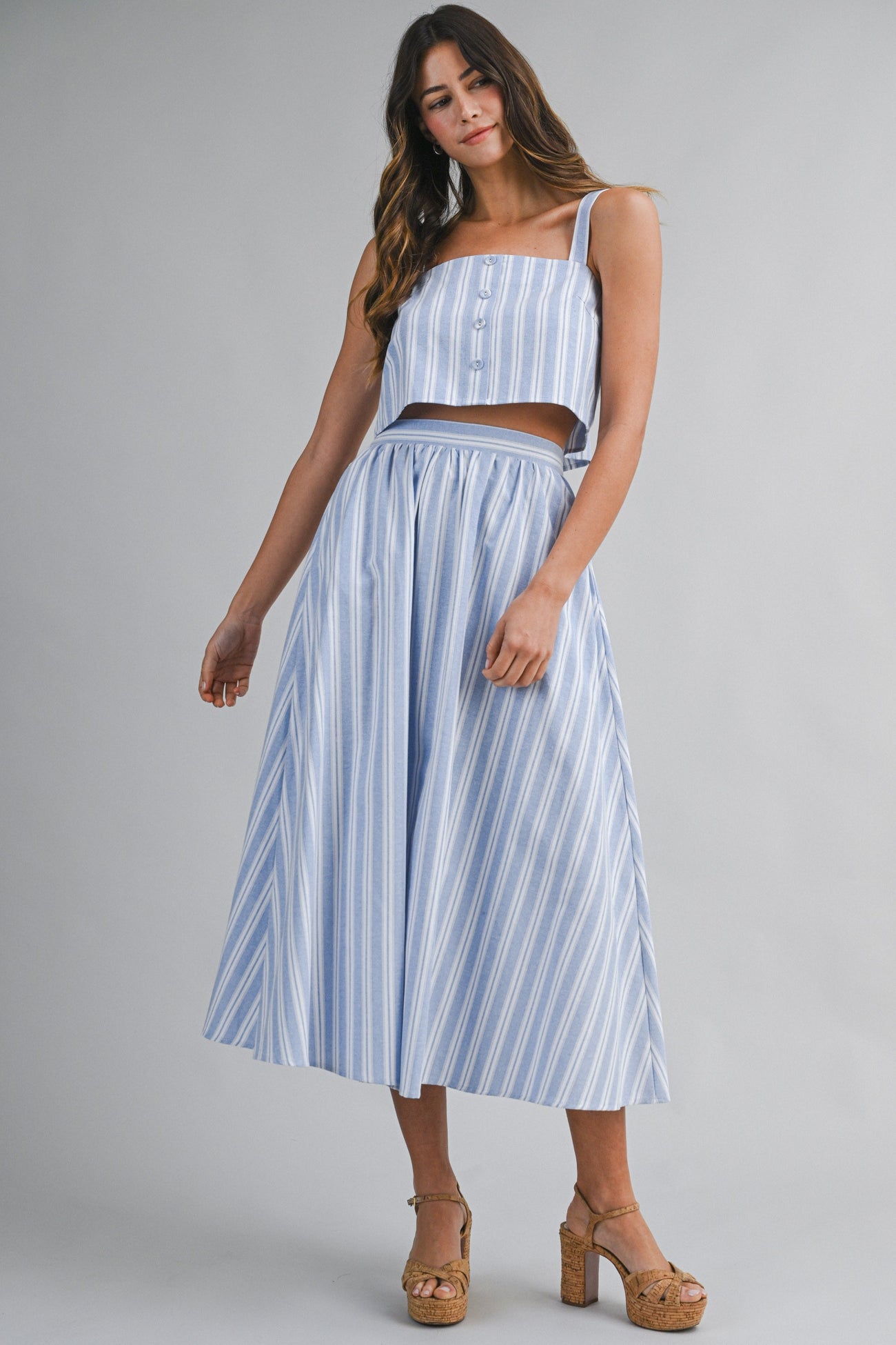 woman wearing a striped blue two-piece set featuring a cropped top and a high-waisted skirt
