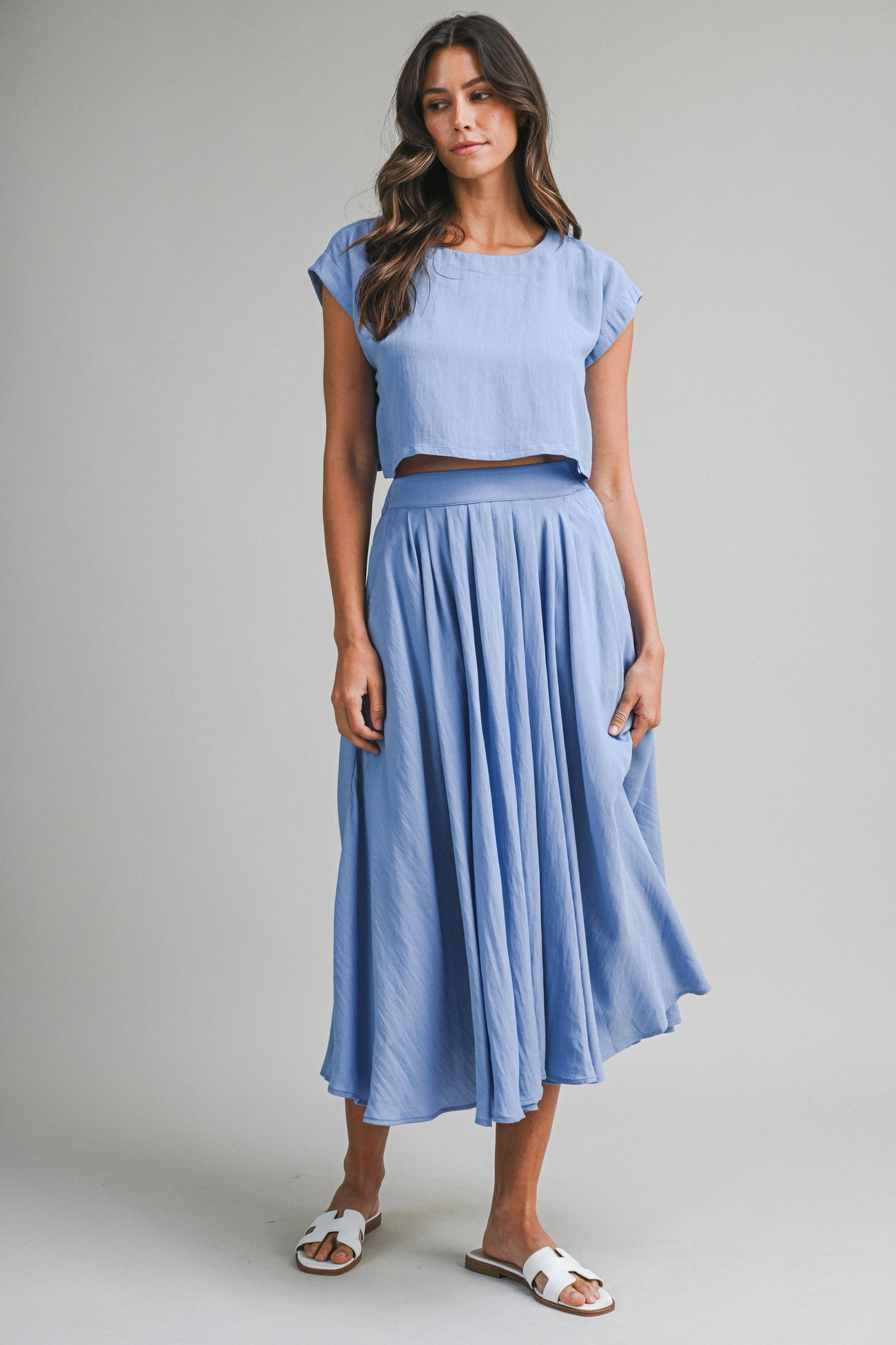 woman wearing a light blue cropped top and matching flowing midi skirt with sandals