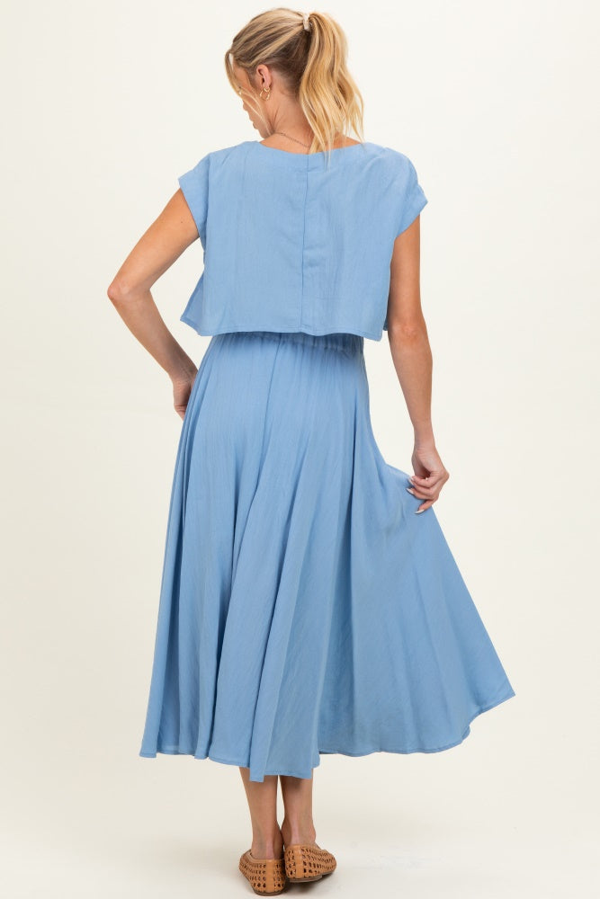 woman wearing a light blue maternity dress with a flowy skirt and a cropped top, showing the back view