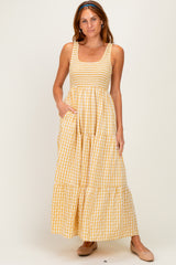 woman wearing a yellow and white gingham sleeveless maxi dress with smocked detailing and side pockets