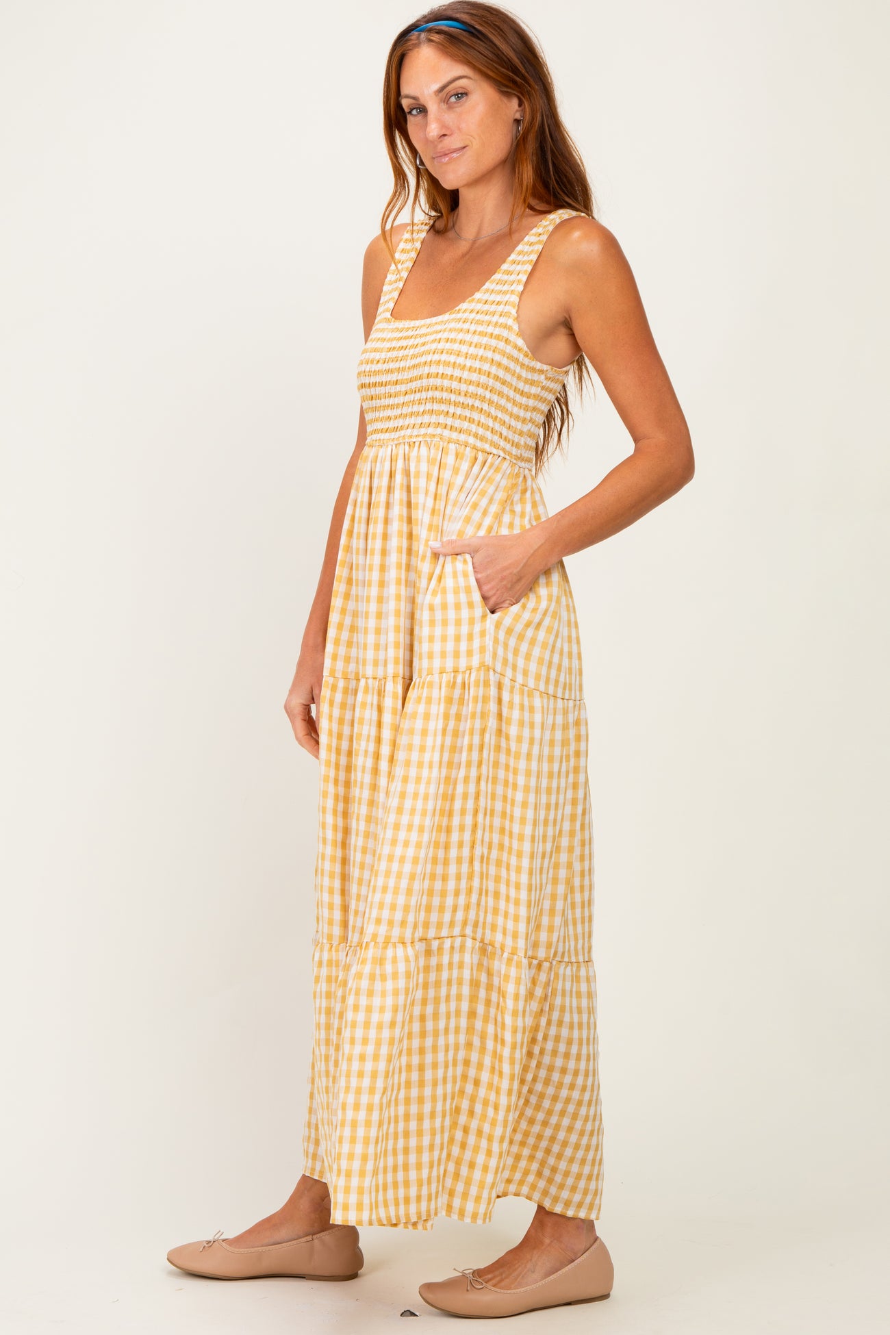 woman wearing a yellow and white gingham print maxi dress with a smocked bodice and pockets