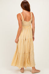 woman wearing a back view of a yellow and white gingham maxi dress with smocked bodice and tiered skirt
