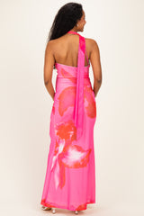 woman wearing a vibrant pink maternity dress with large floral patterns and a halter neck, showing her back