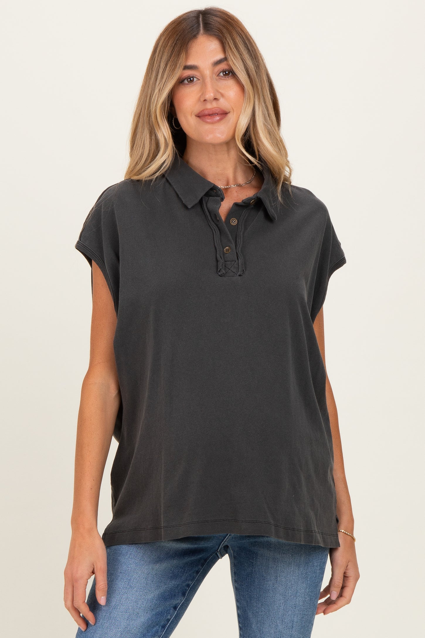 woman wearing a charcoal grey maternity polo shirt with a buttoned placket and rolled sleeves