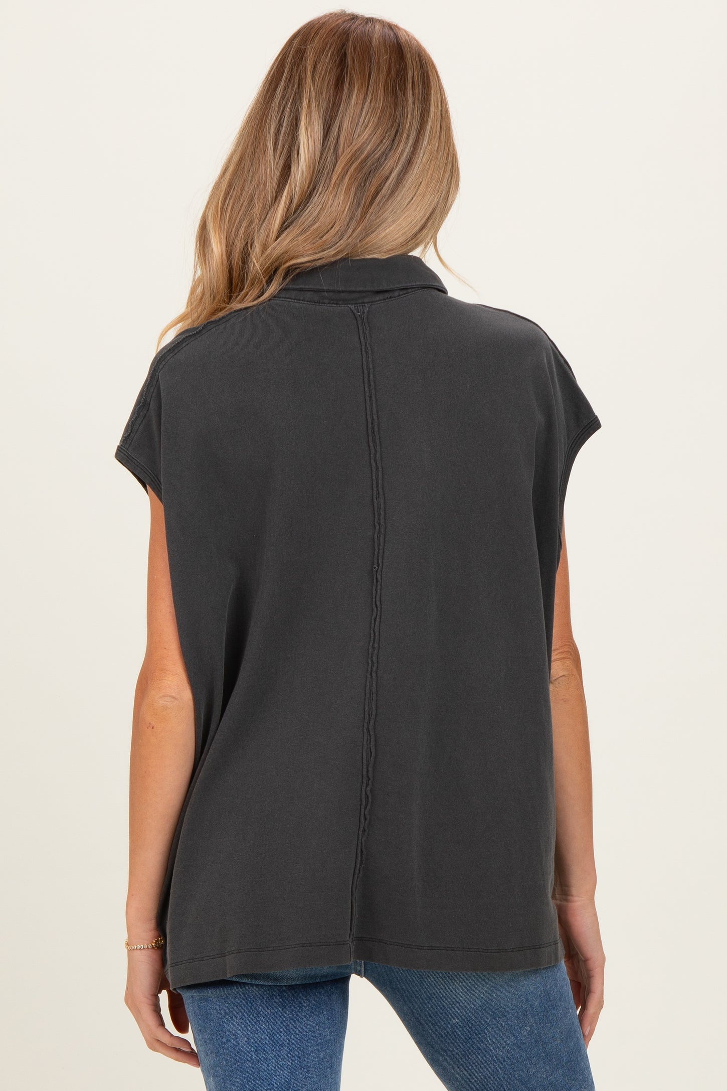 woman wearing a dark gray maternity short sleeve top, showing a relaxed fit and back seam detail