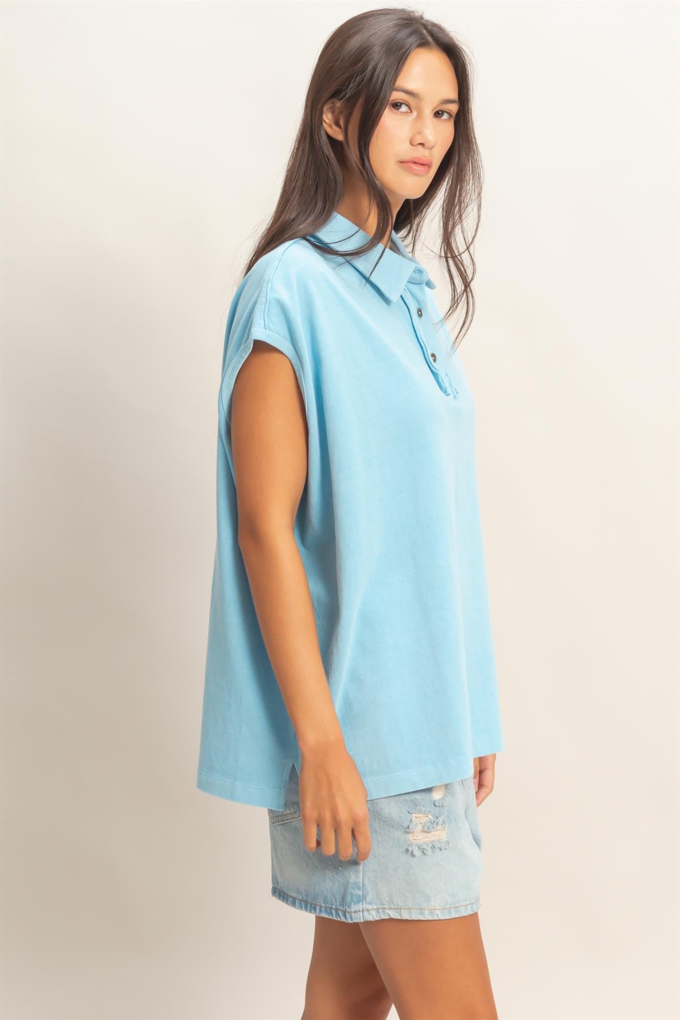 woman wearing a light blue short sleeve polo shirt and distressed denim mini skirt