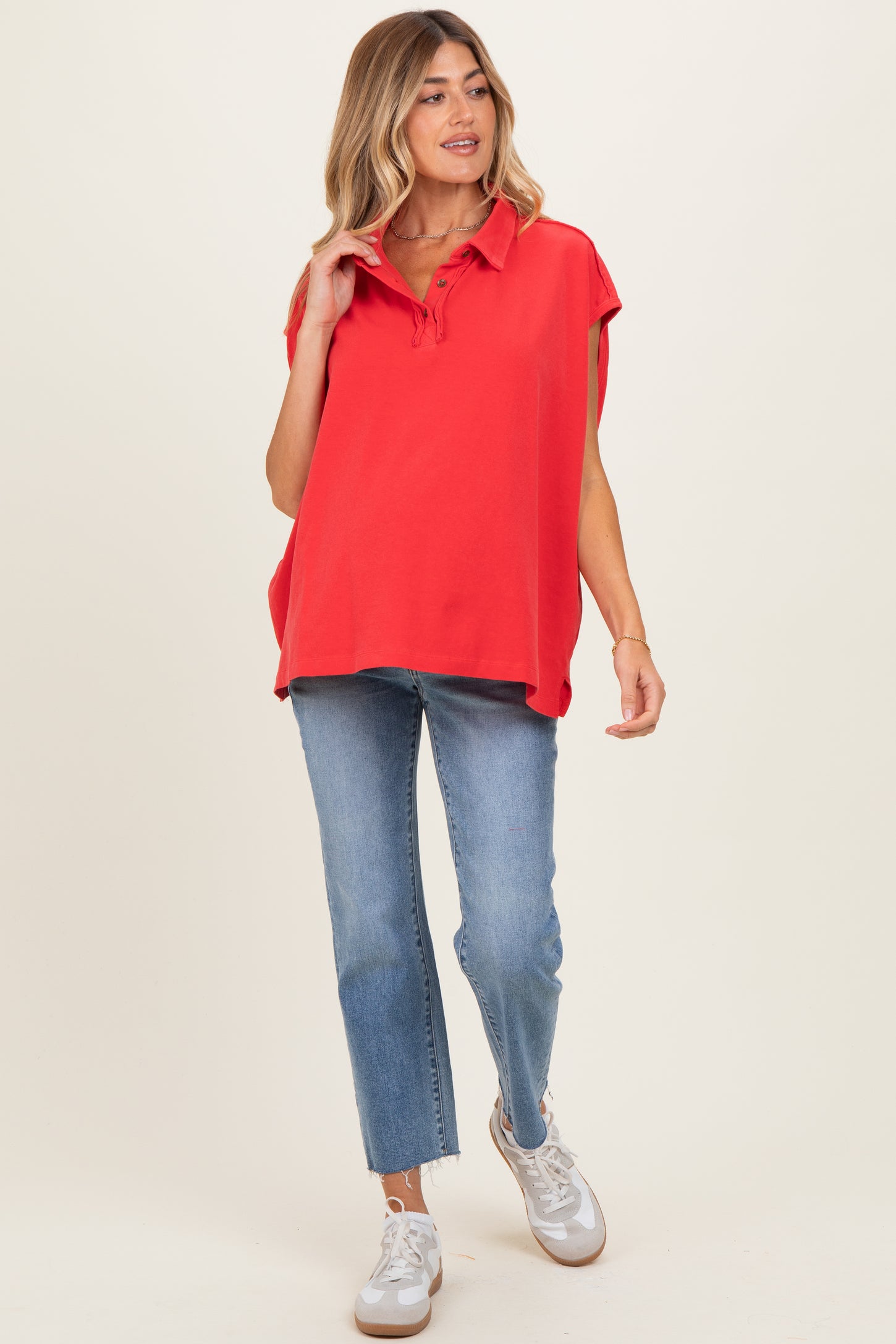 woman wearing a red maternity polo-style top with short sleeves and light blue jeans