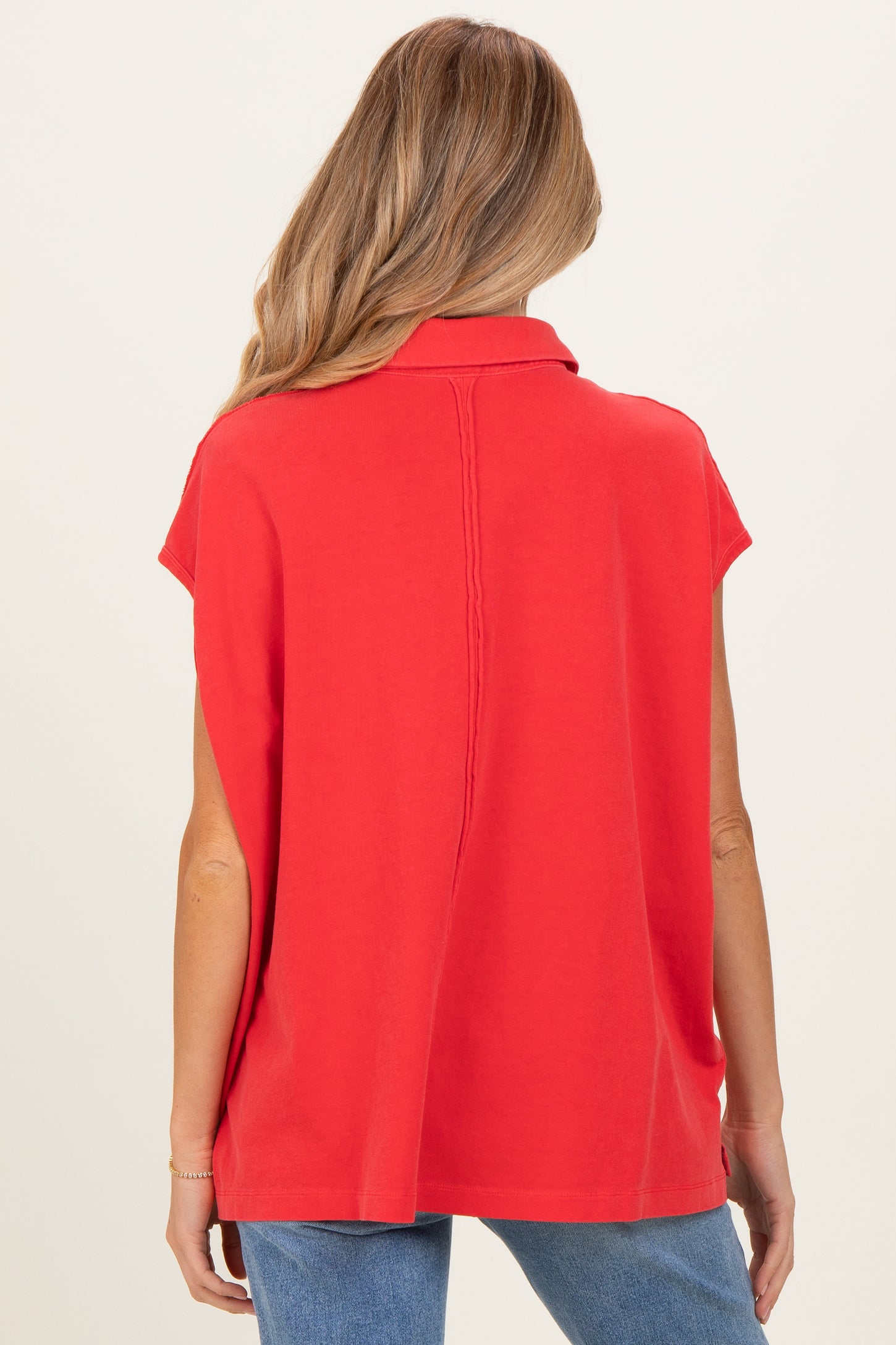 woman wearing a red maternity top with short sleeves and a collar, seen from the back