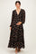 woman wearing a black floral maternity maxi dress with long sleeves and a tiered skirt, holding her baby bump