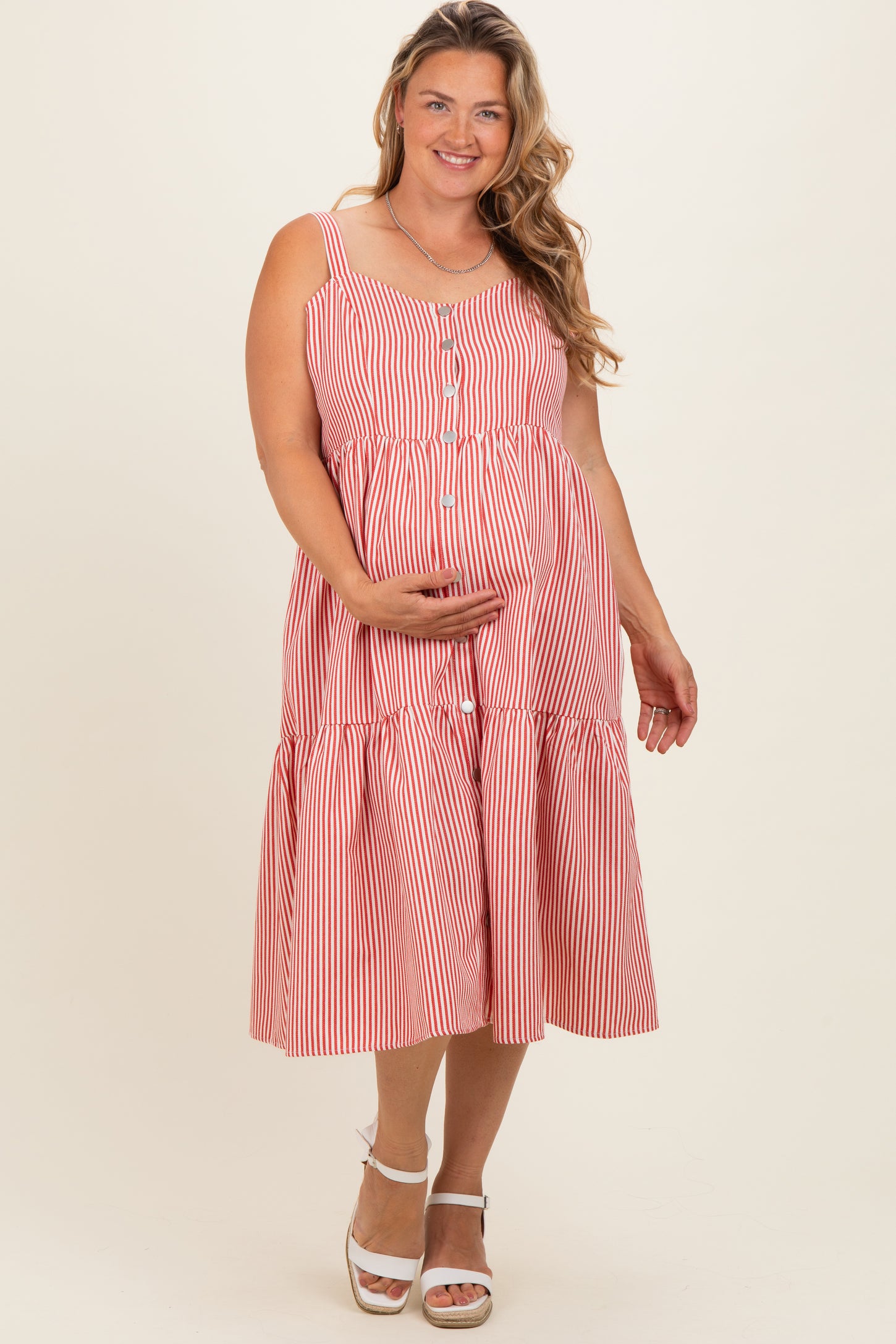 woman wearing a red and white striped maternity plus dress with buttons and a tiered skirt, showcasing her baby bump