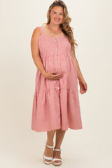 woman wearing a red and white striped maternity plus dress with buttons and a tiered skirt, showcasing her baby bump