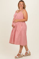 woman wearing a red and white striped maternity plus sundress, showing her baby bump while smiling