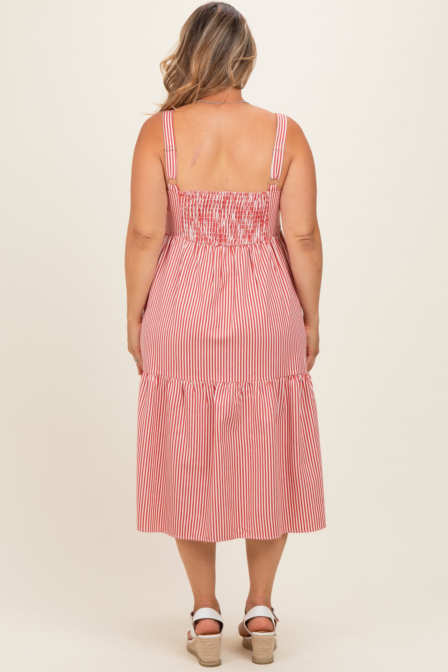 woman wearing a red and white striped maternity plus dress with a smocked bodice and tiered skirt, styled for summer