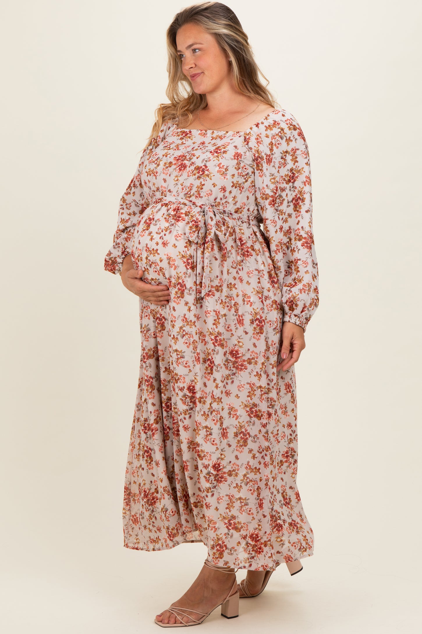 woman wearing a floral maternity plus maxi dress with a tie waist and holding her baby bump