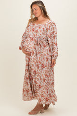woman wearing a floral maternity plus maxi dress with a tie waist and holding her baby bump