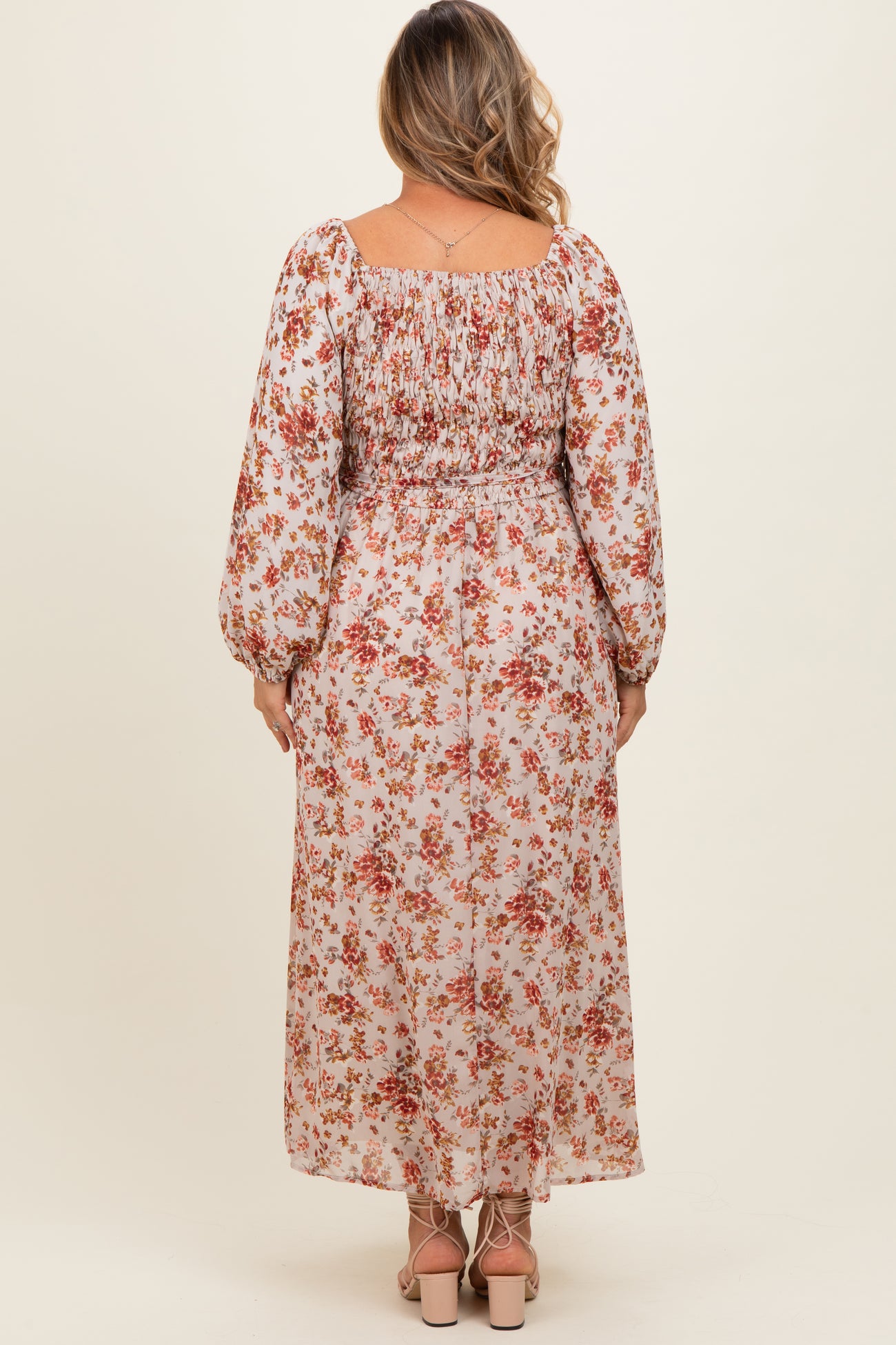 woman wearing a floral maxi maternity dress with long sleeves and a smocked back, showing off her baby bump
