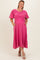 woman wearing a pink maternity plus dress with puff sleeves and pockets, standing against a neutral background