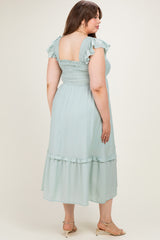 woman wearing a light green maternity plus midi dress with ruffled sleeves and a smocked bodice, seen from the back