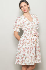 woman wearing a white floral wrap dress with short ruffled sleeves and a tied waist