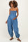 woman wearing a denim maternity jumpsuit with smocked bodice and balloon legs, showing her baby bump