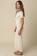 woman wearing a cream-colored knitted maxi dress with a denim collar and short sleeves, standing sideways