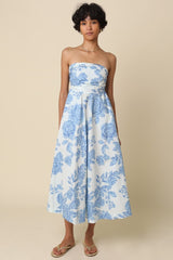 woman wearing a strapless midi dress with a blue floral pattern and a fitted waist, standing against a neutral background