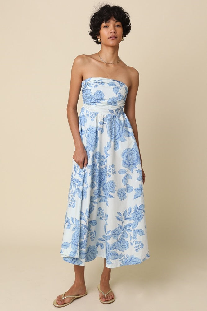 woman wearing a strapless blue floral maxi dress with a fitted bodice and flowy skirt