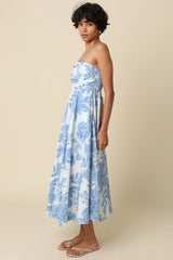 woman wearing a strapless maxi dress with a floral blue and white pattern and a flowy skirt