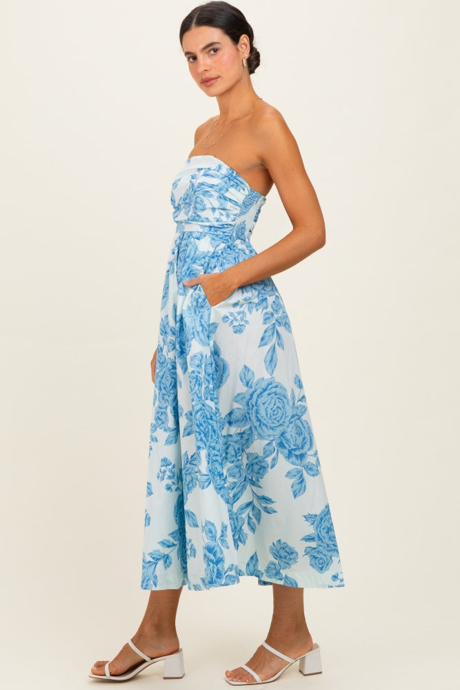 woman wearing a strapless blue floral midi dress with pockets and a flowing skirt