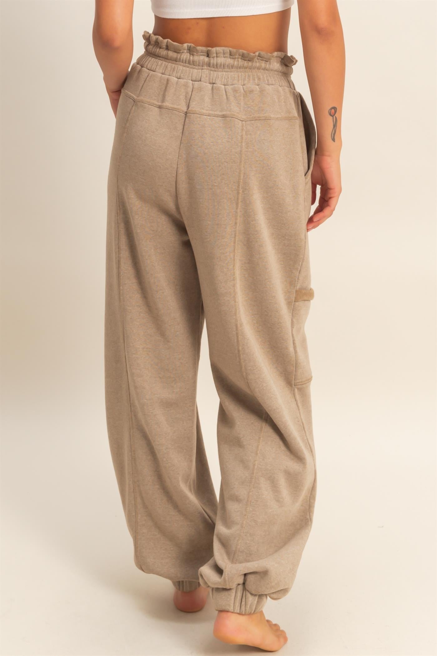 woman wearing beige high-waisted wide-leg lounge pants with an elastic waistband and side pockets