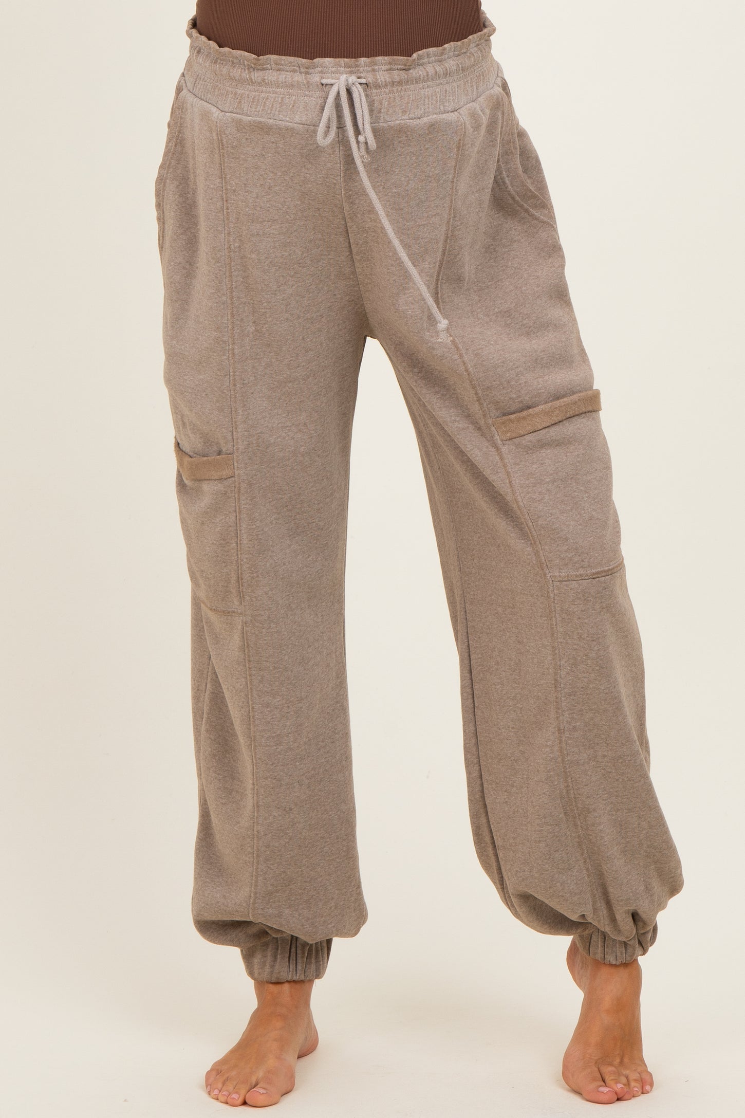 woman wearing beige maternity jogger pants with a drawstring waist and cuffed ankles