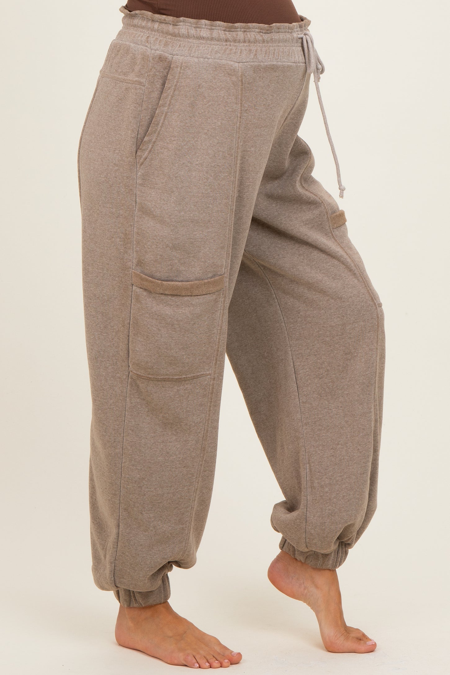 maternity wear light brown jogger pants with side pockets and elastic cuffs, model showing baby bump