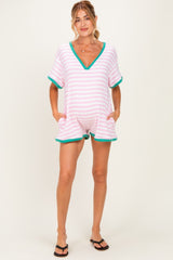 woman wearing a pink and white striped maternity romper with a v-neck and green trim, showing her baby bump