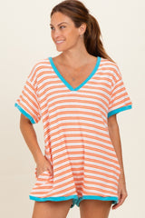 woman wearing a striped orange and white oversized v-neck tee with turquoise trim and pockets