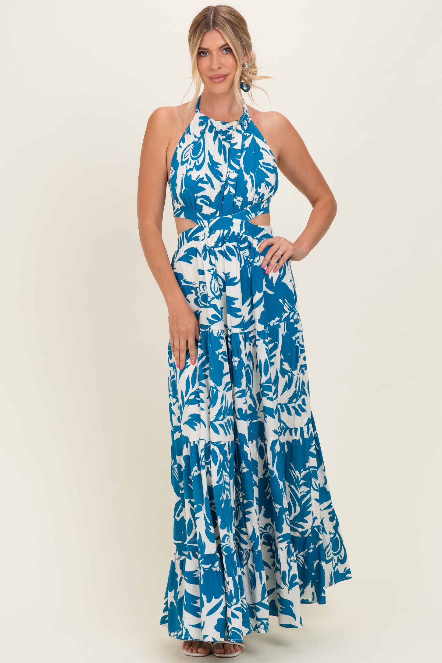 woman wearing a blue and white floral halter neck maxi dress with cut-out details and a flowy skirt