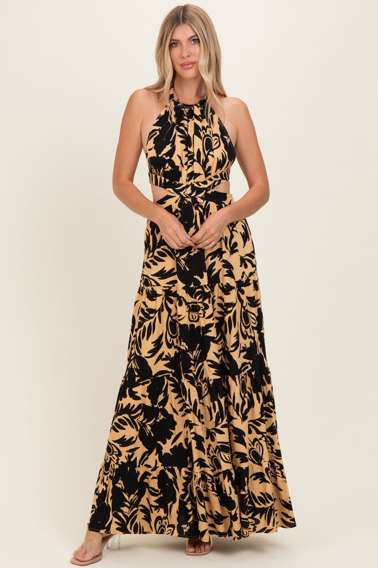 woman wearing a black and tan floral print halter maxi dress with cut-out details and a flowing skirt