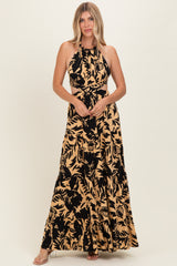 woman wearing a black and tan floral print halter maxi dress with cut-out details and a flowing skirt