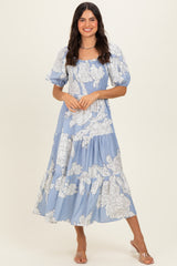 woman wearing a blue floral midi dress with puff sleeves and a tiered skirt