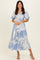 woman wearing a blue floral midi dress with puff sleeves and a tiered skirt