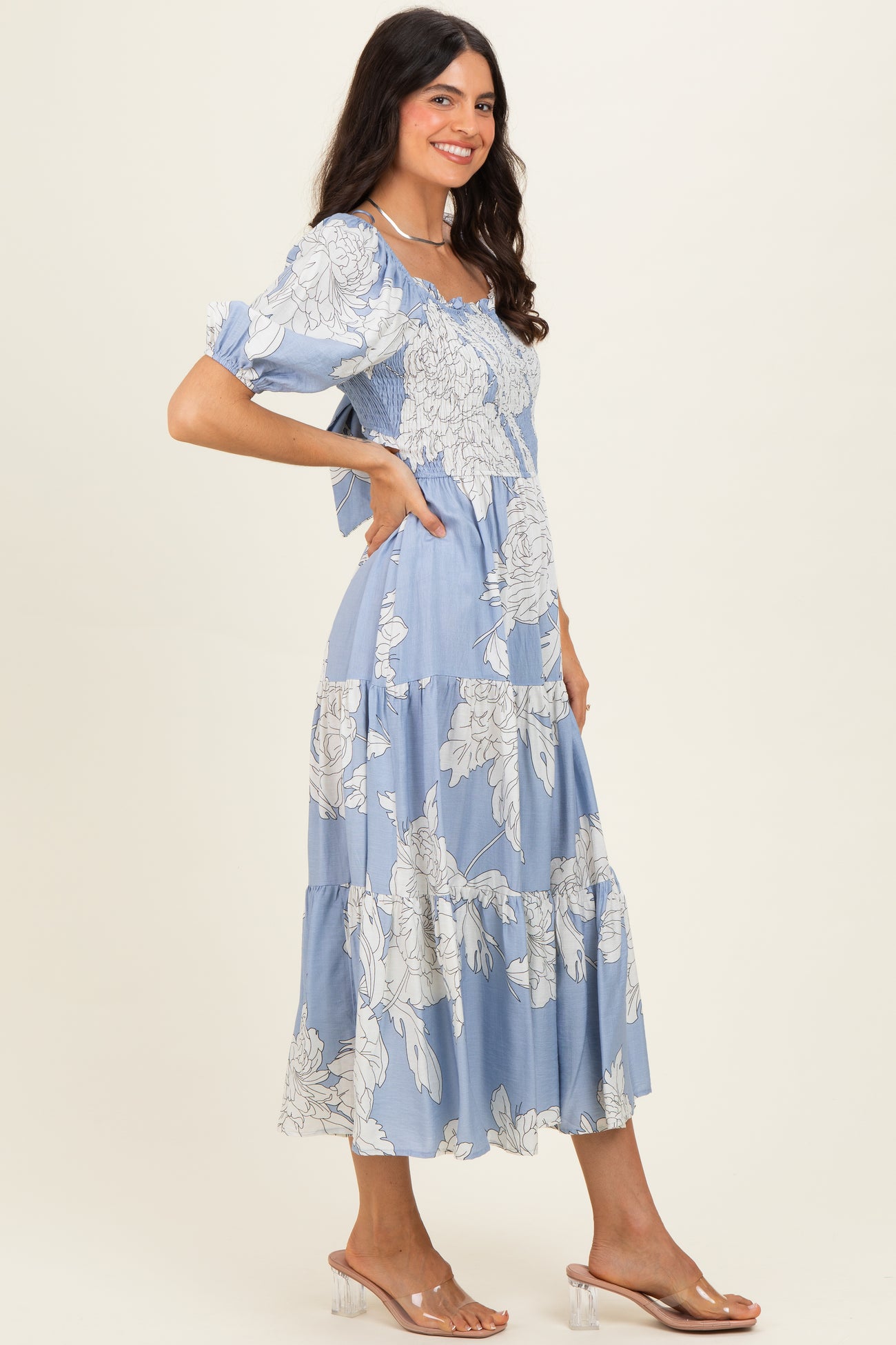 woman wearing a light blue floral print maxi dress with puff sleeves and a tiered skirt
