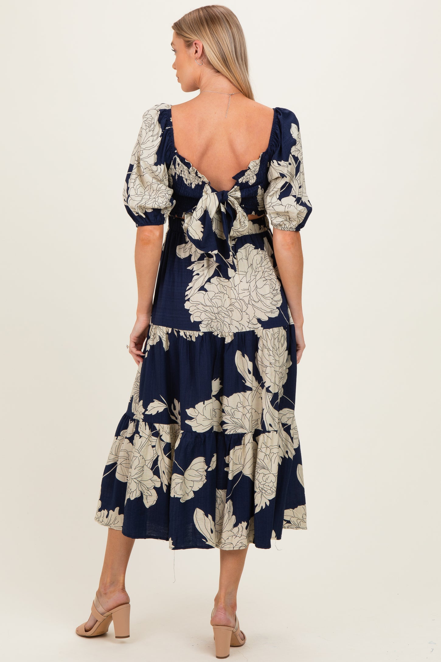 woman wearing a navy floral print maternity maxi dress with puffed sleeves and a tie-back detail