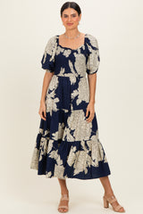 woman wearing a navy blue floral midi dress with puff sleeves and a smocked bodice, standing and smiling