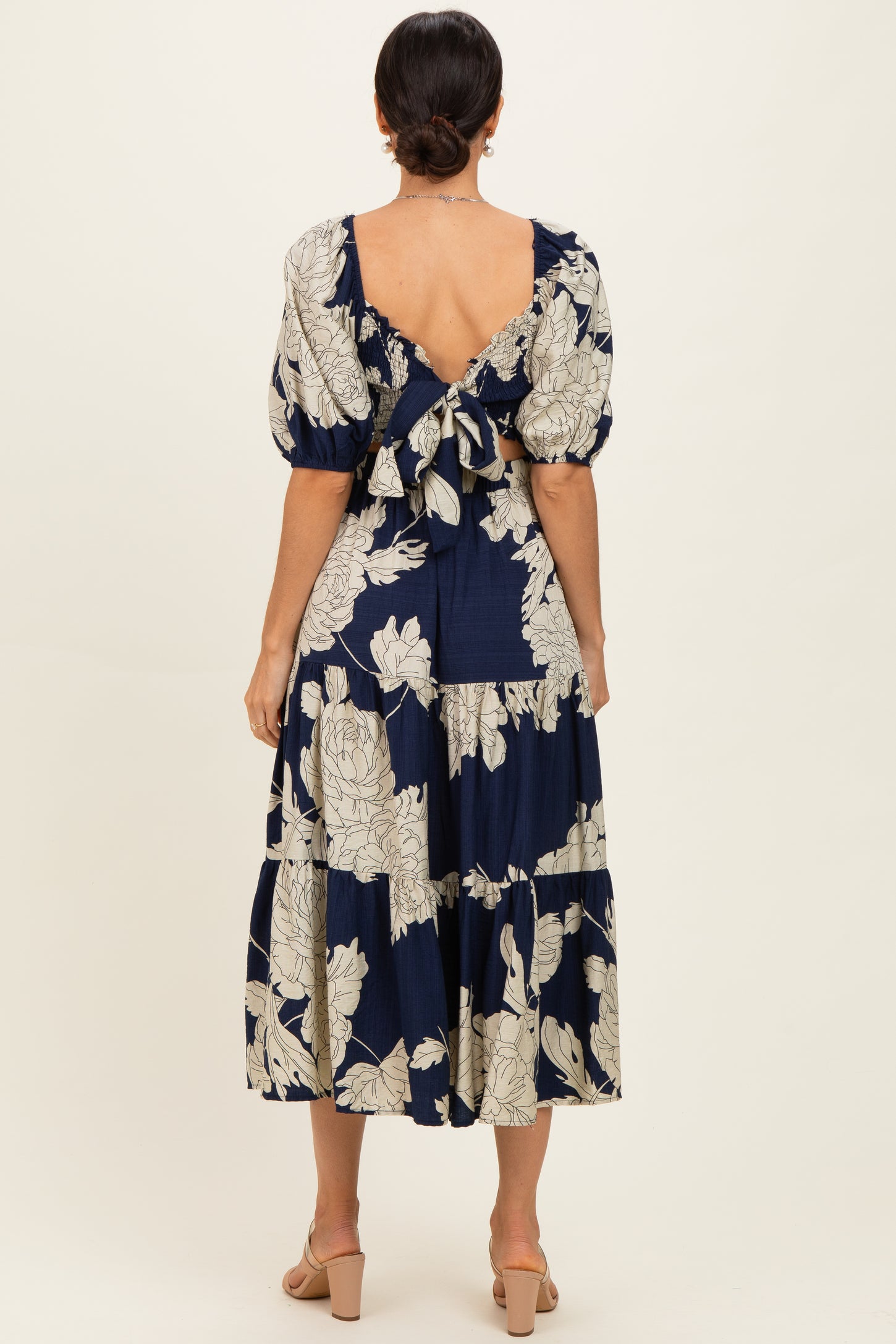 woman wearing a navy floral midi dress with puff sleeves and a back tie detail