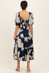 woman wearing a navy floral midi dress with puff sleeves and a back tie detail