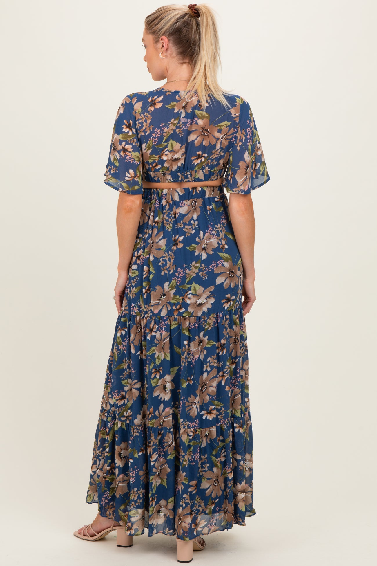 woman wearing a floral maxi maternity dress with short sleeves and a belt, showing the back view