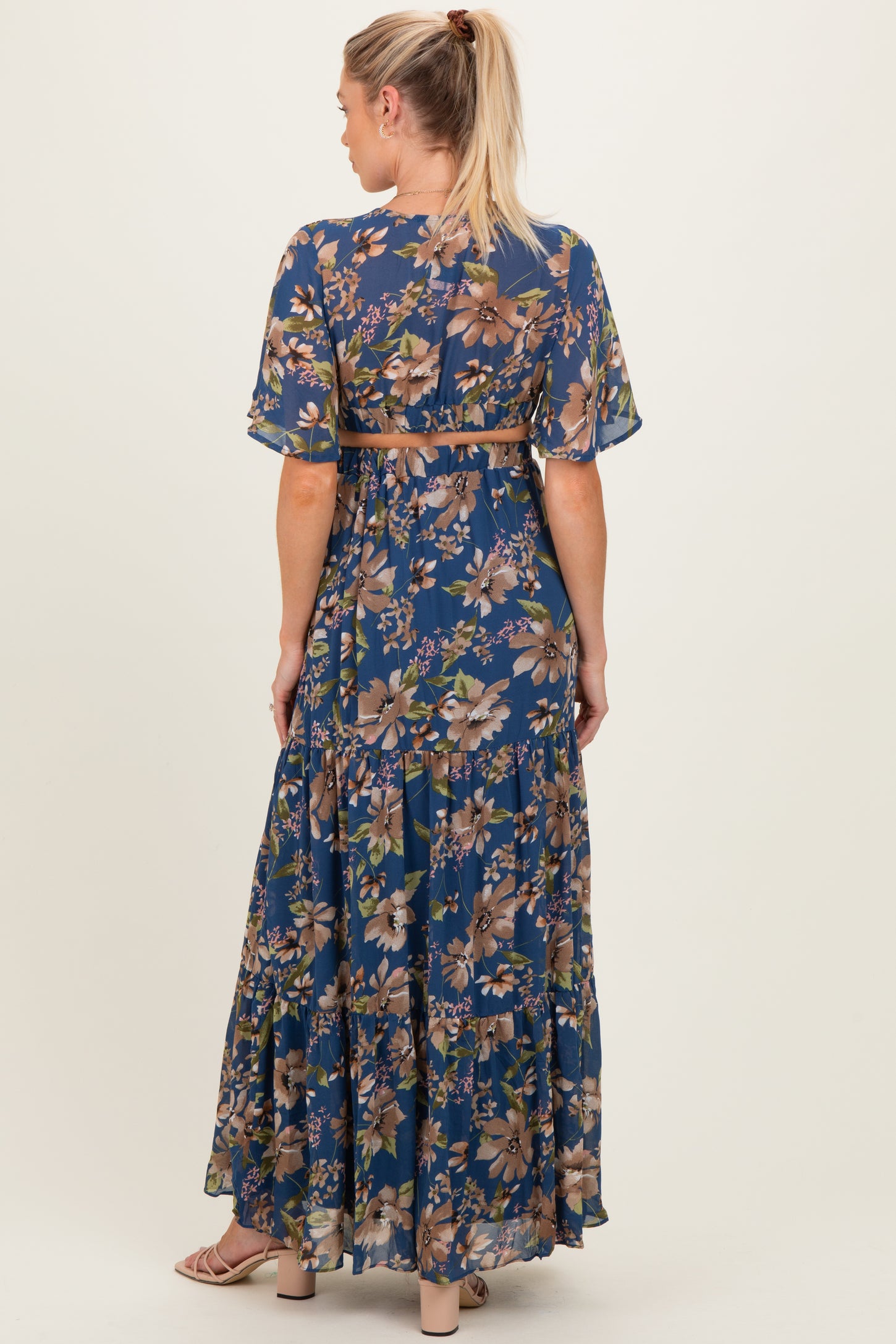 woman wearing a floral maxi maternity dress with short sleeves and a belt, showing the back view