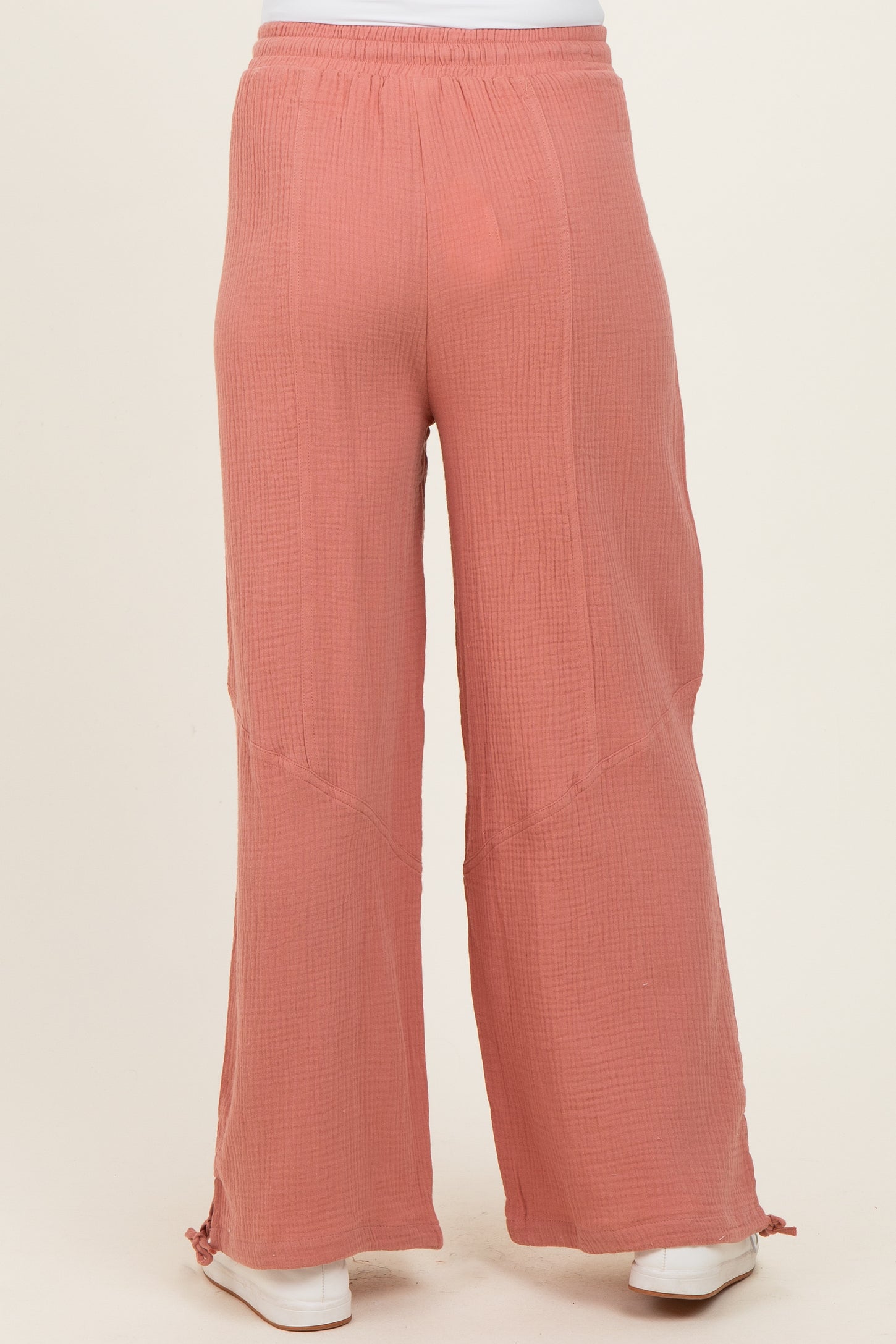 maternity wear in a coral pink loose fitting gauze pant with wide leg and side slits at the hem