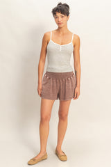 woman wearing a striped tank top and soft brown shorts with an elastic waistband