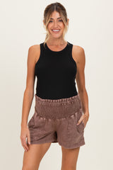 woman wearing a black ribbed tank top and brown smocked waist maternity shorts with pockets